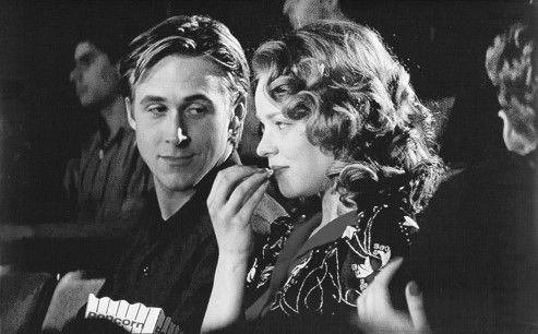 black and white photograph of two people sitting next to each other at a movie theater