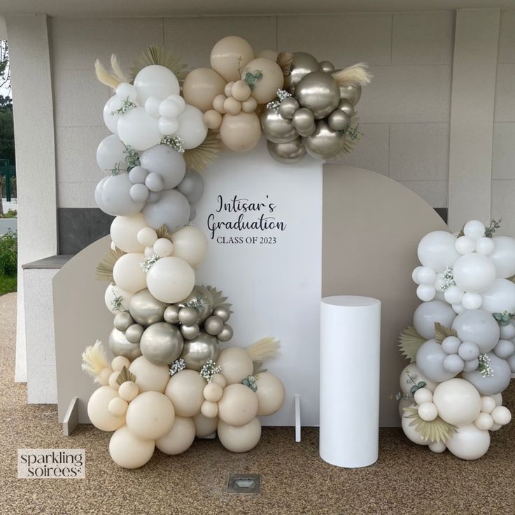 balloons are arranged in the shape of an arch for a graduation party with white and silver decorations