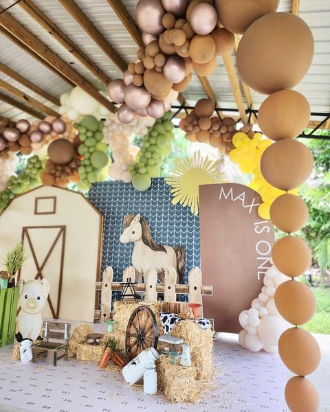 a table topped with hay bales covered in animals and balloons hanging from the ceiling