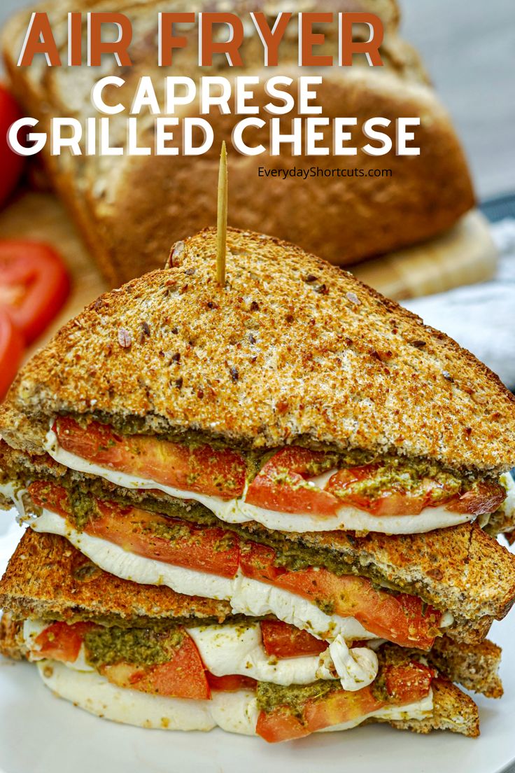 a grilled cheese sandwich on a white plate with tomatoes and bread in the background