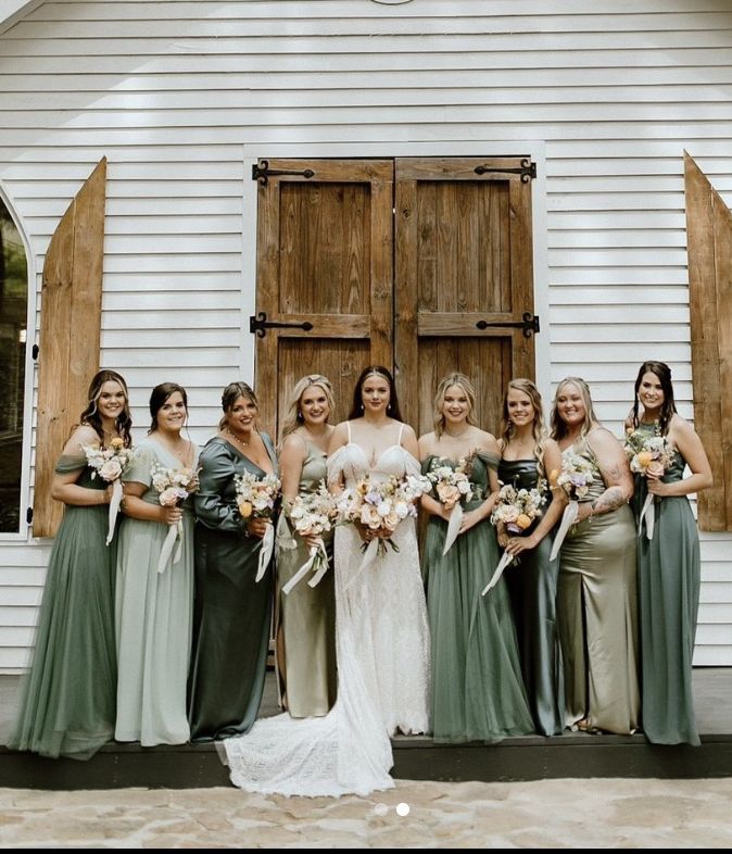 a group of women standing next to each other in front of a white building holding bouquets