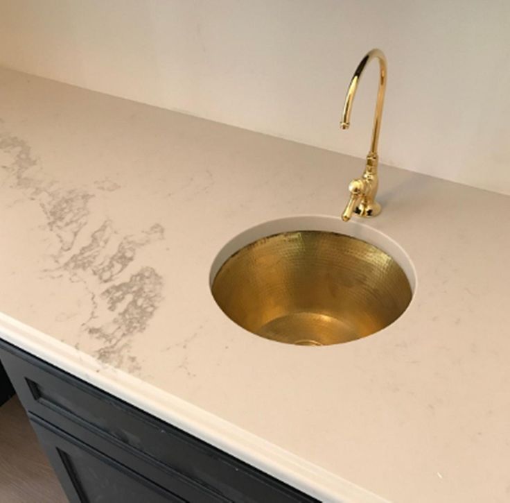 a white counter top with a gold sink