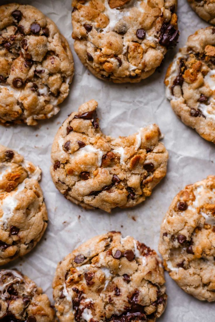 cookies with chocolate chips and marshmallows are arranged on a sheet of wax paper