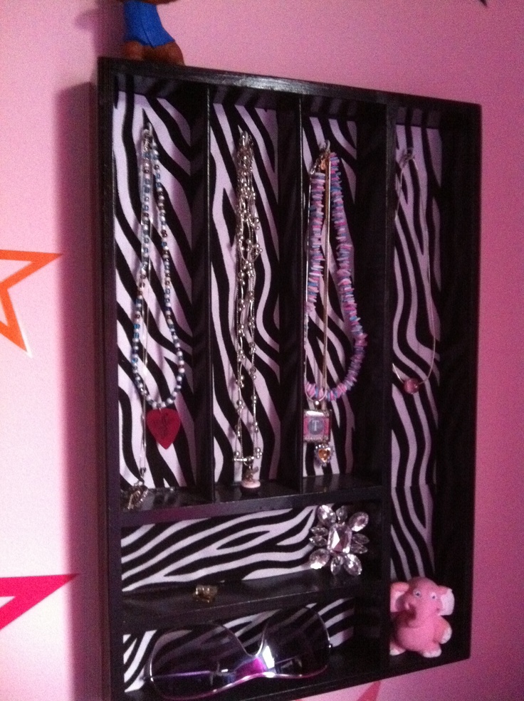 a black and white zebra print wall mounted jewelry rack with several necklaces on it