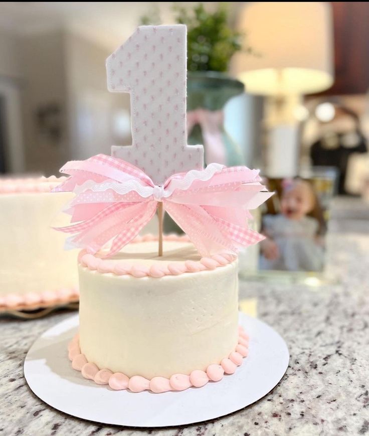 the first birthday cake is decorated with pink and white icing