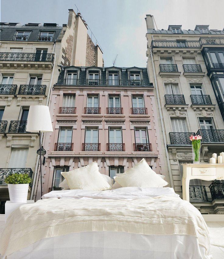 a large bed sitting in front of two tall buildings with balconies on each side