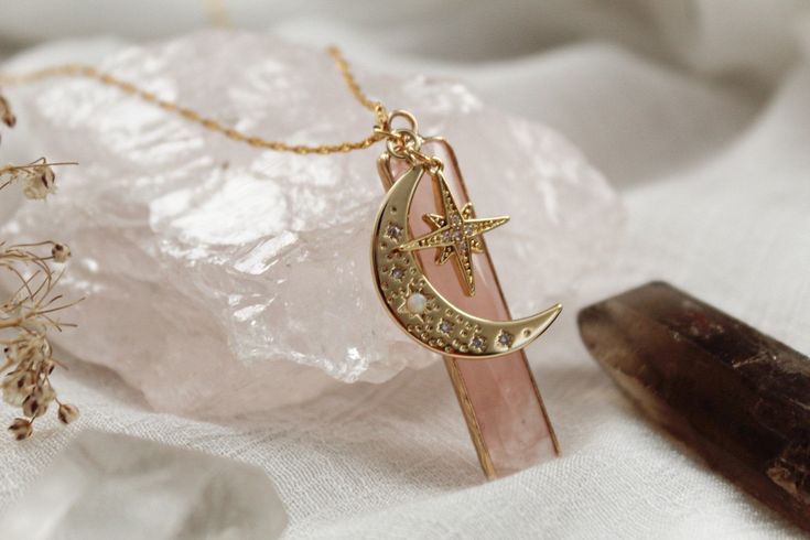 The Universe necklace is a stunning necklace filled with mystical charms from beyond the stars. Rose Quartz is the stone of universal love, Opal contributes to cosmic conscientiousness, and the Moon and Stars balance your chakras. They are a guiding light amongst the darkness. This beautiful piece is made for those looking for direction from the night sky. WHAT IS GOLD-FILLED? Gold-filled items are stunning jewels that are second only to pure gold. These pieces have gold that is mechanically bon Celestial Style Birthstone Jewelry, Spiritual Star Charm Pendant Jewelry, Celestial Sterling Silver Crystal Necklace With Moon Charm, Elegant Moon-shaped Charm Necklaces, Elegant Moon Shaped Charms Necklace, Elegant Moon Shaped Necklace With Charms, Elegant Moon-shaped Necklace With Charms, Spiritual Moon Charm Jewelry For Wedding, Ethereal Pendant Jewelry For Gifts