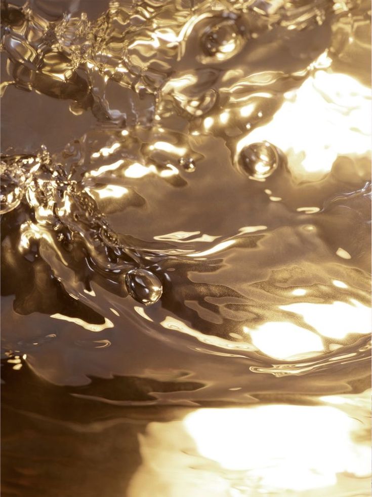 water is flowing down the side of a metal tank with sunlight shining on it and bubbles in the water