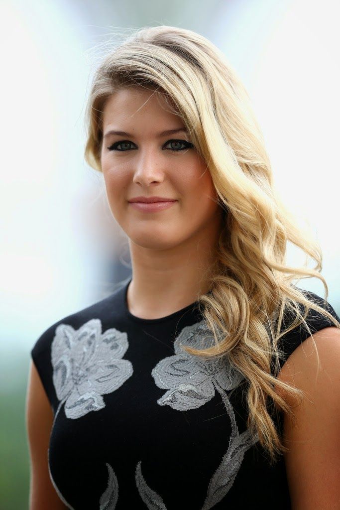 a woman with long blonde hair wearing a black and white dress smiling at the camera