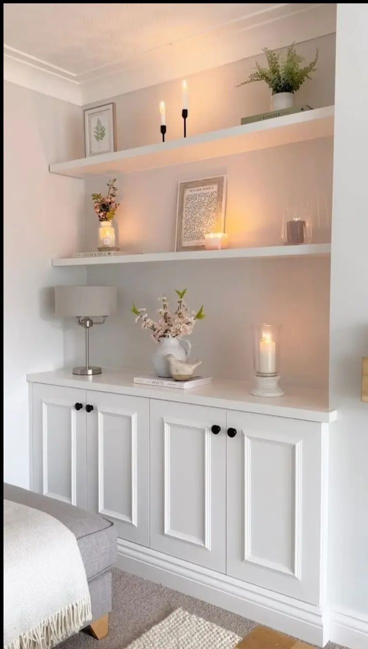 a living room with white shelves and candles