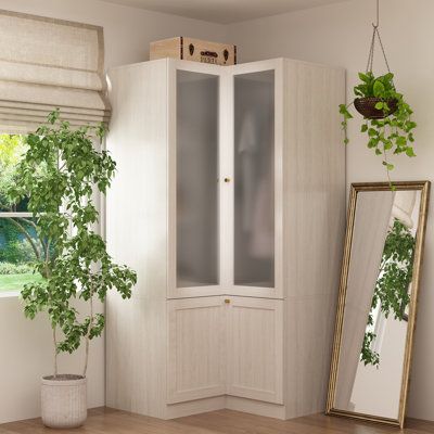 a white cabinet sitting next to a window filled with green plants