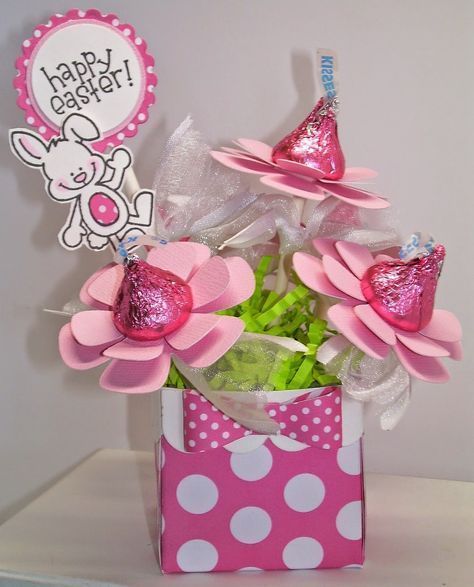 a pink gift bag filled with candy and flowers on top of a white table next to a sign that says happy birthday