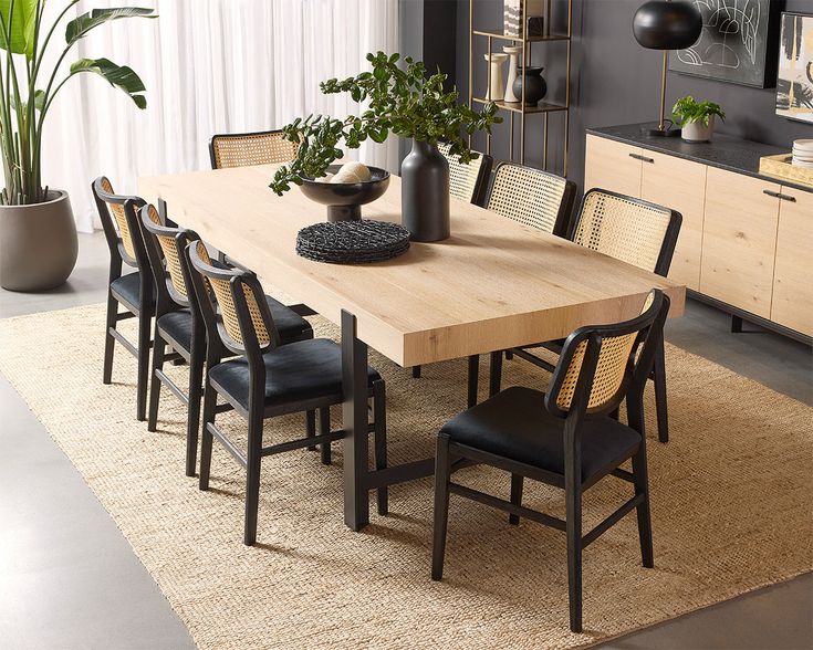 a dining room table with black chairs and a potted plant