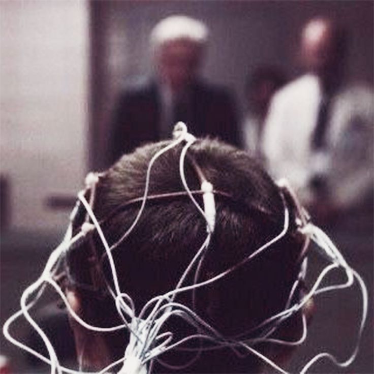 the back of a woman's head with wires attached to it and two people in the background