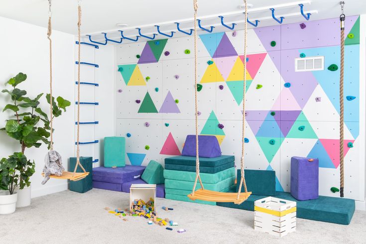 an indoor play area with swings, toys and climbing walls in pastel hues