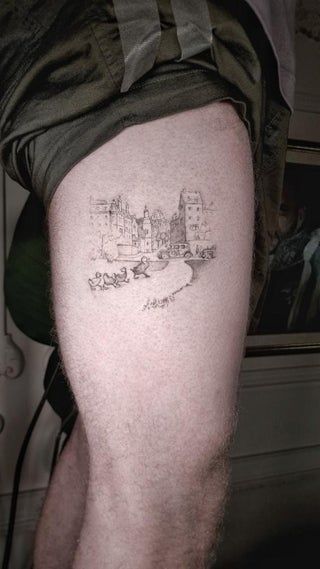 a man's leg with a small cityscape tattoo on his left thigh