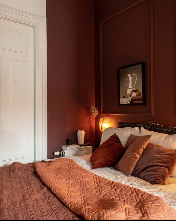 a bedroom with red walls and orange bedding