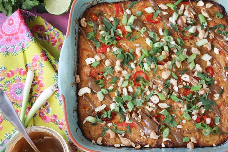 a casserole dish with meat, vegetables and sauces on the table next to it