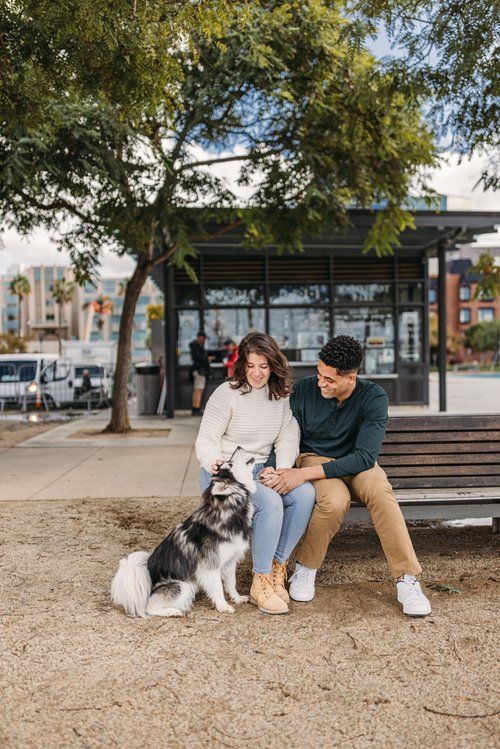 a man and woman sitting on a bench with their dog