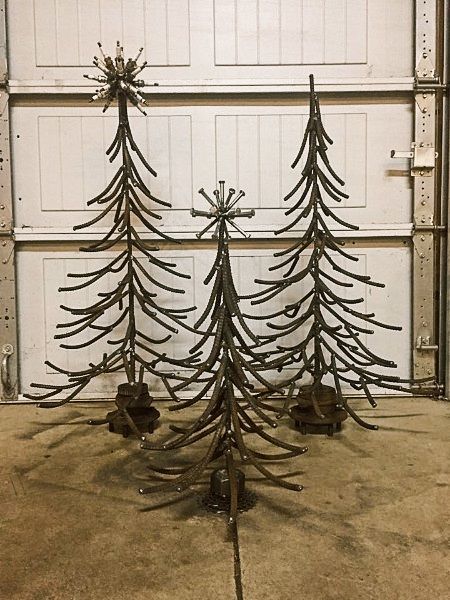 a metal christmas tree sitting on top of a cement floor next to a garage door