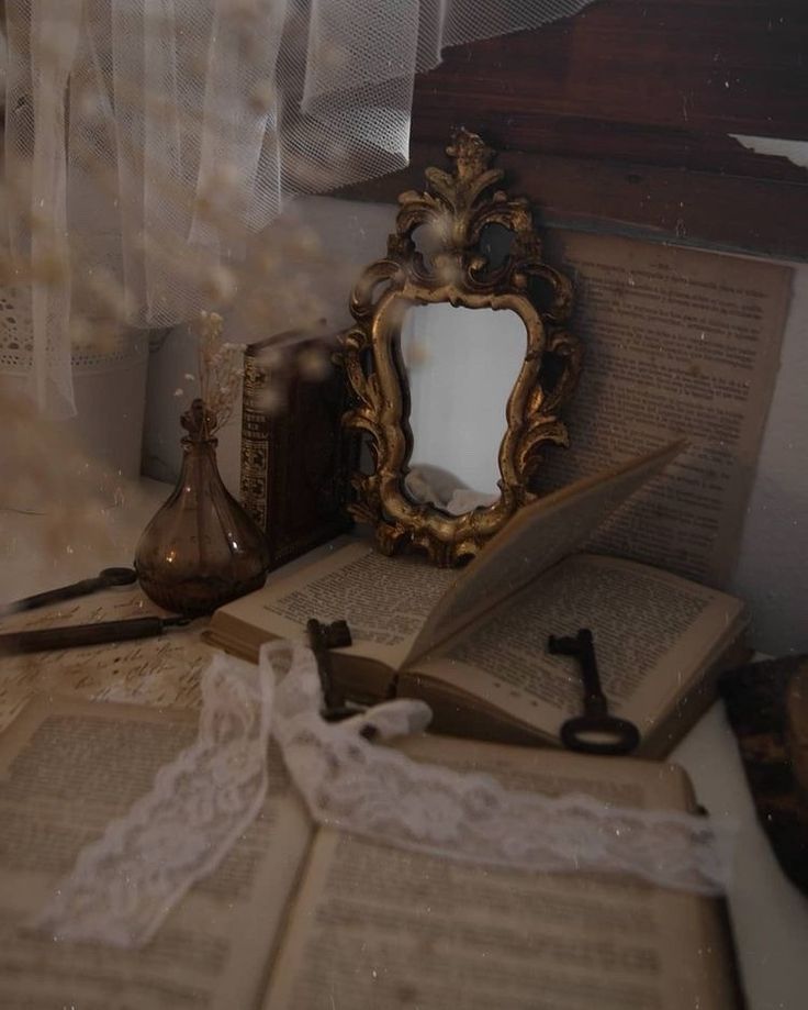 an open book sitting on top of a table next to a mirror and other items