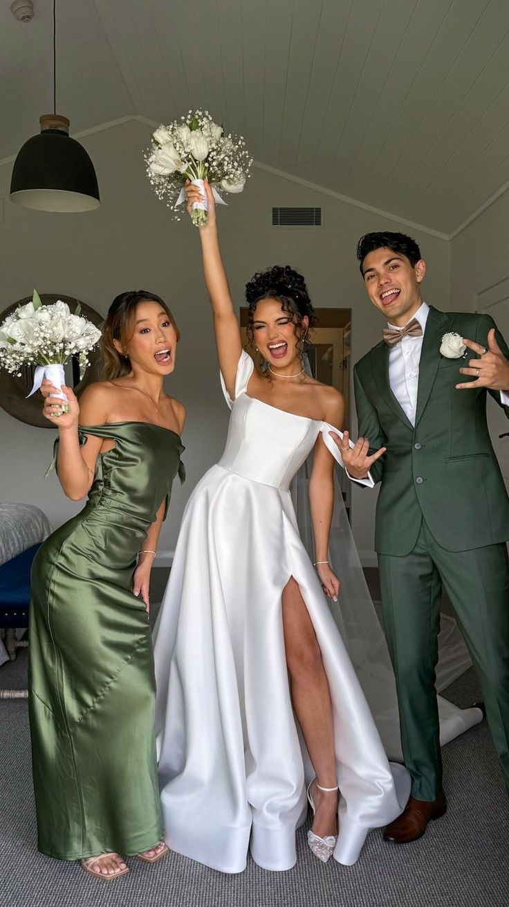 three people dressed in green and white posing for the camera with their bouquets up