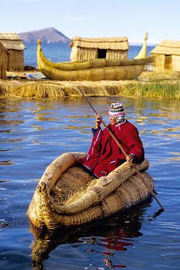 a man in a red jacket is rowing a boat made out of reeds on the water