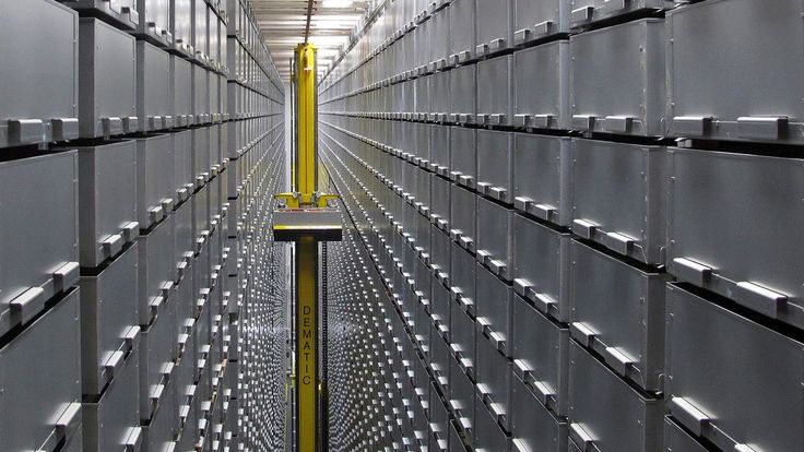 the inside of a large storage room with lots of metal boxes on each side and yellow poles in the middle