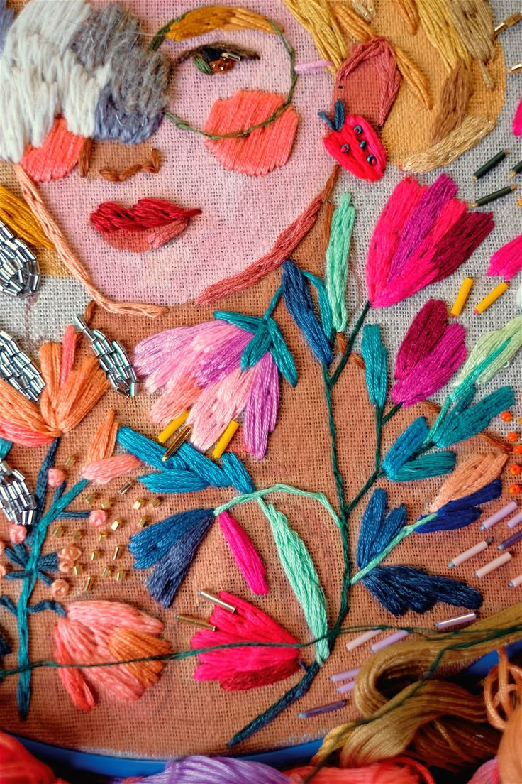 a woman's face is surrounded by colorful thread and needle work on a piece of fabric