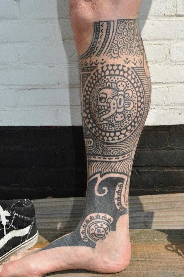 a man's leg with an intricate tattoo design on the lower part of his leg