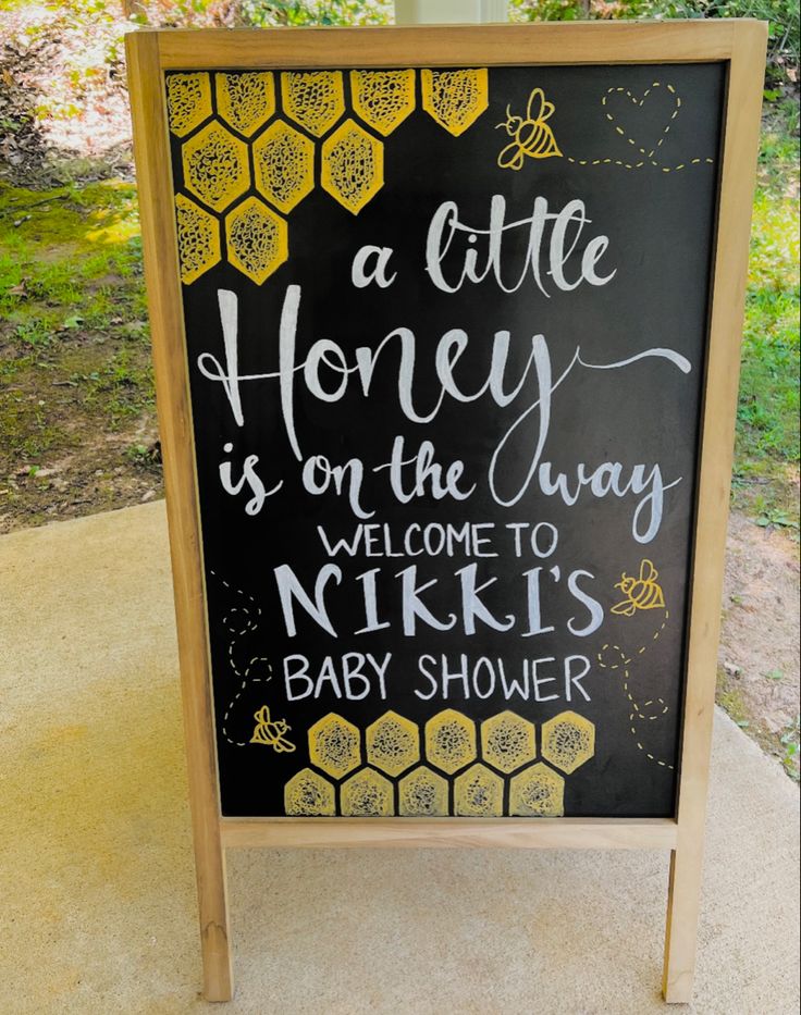 a chalkboard sign that says a little honey is on the way, welcome to nick's baby shower