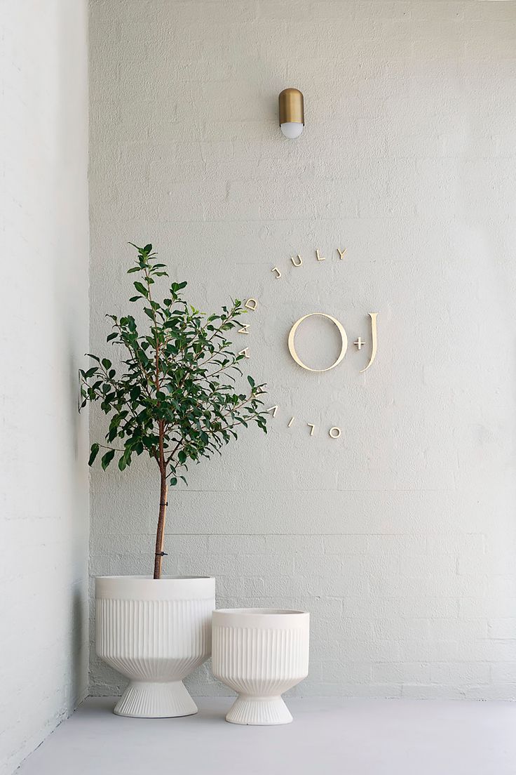 two white vases sitting on top of a table next to a wall mounted clock