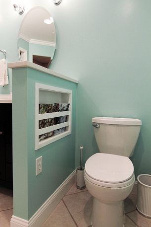 a white toilet sitting inside of a bathroom next to a sink under a vanity mirror