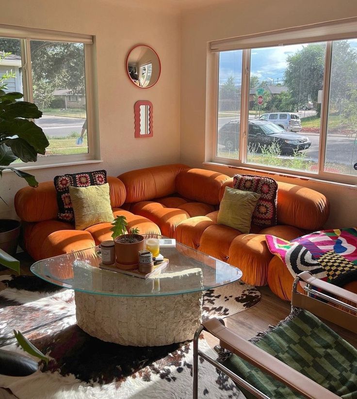 a living room with orange couches and large windows overlooking the street in front of it