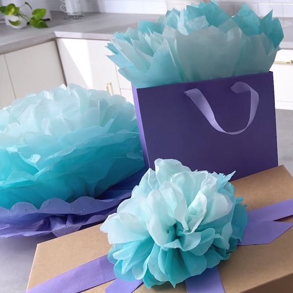 two blue tissue pom poms sitting on top of a brown box