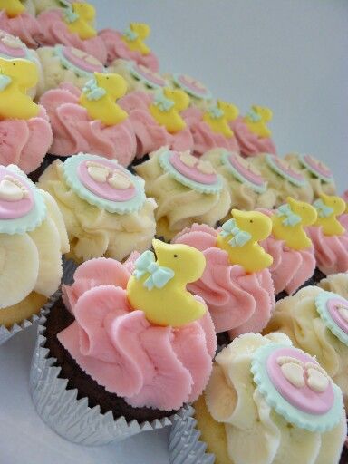 cupcakes decorated with pink, yellow and white frosting are arranged in rows