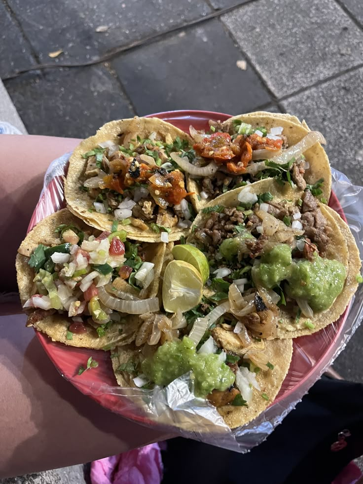 three tacos are on a plate with onions and guacamole