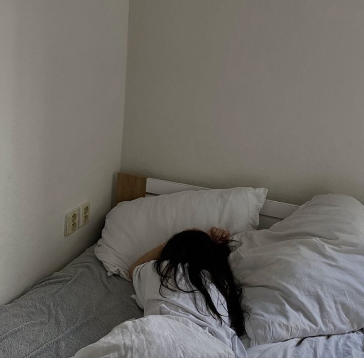 a woman laying in bed with her head on the pillow