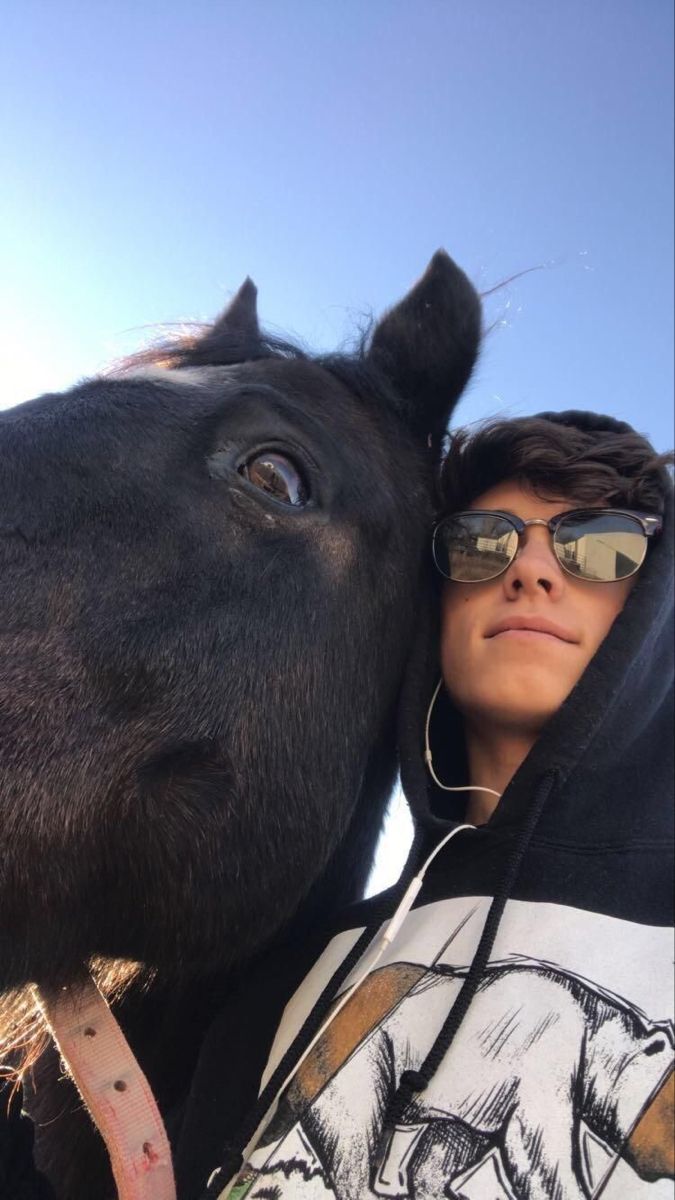 a woman is hugging a horse with her face close to it's face and wearing sunglasses