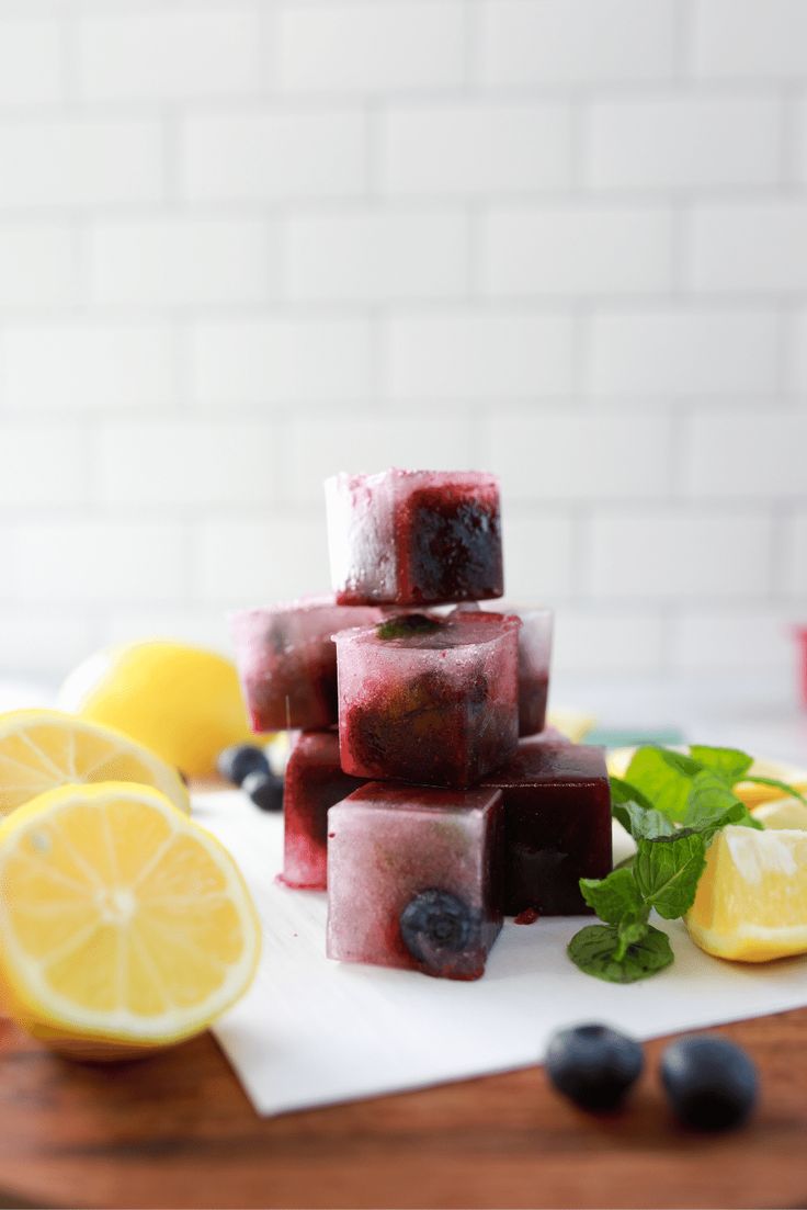 several cubes of ice with blueberries, lemon and mint on a white plate