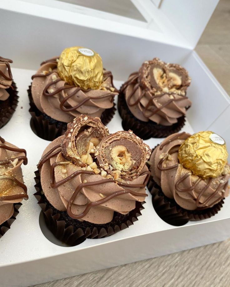 chocolate cupcakes with gold decorations in a white box