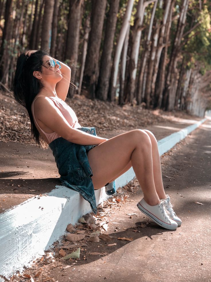 a woman sitting on the side of a road with her legs crossed and eyes closed