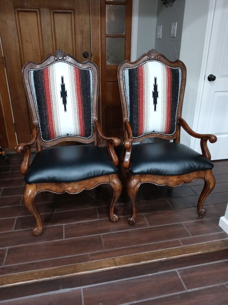 two wooden chairs sitting on top of a hard wood floor next to a white door