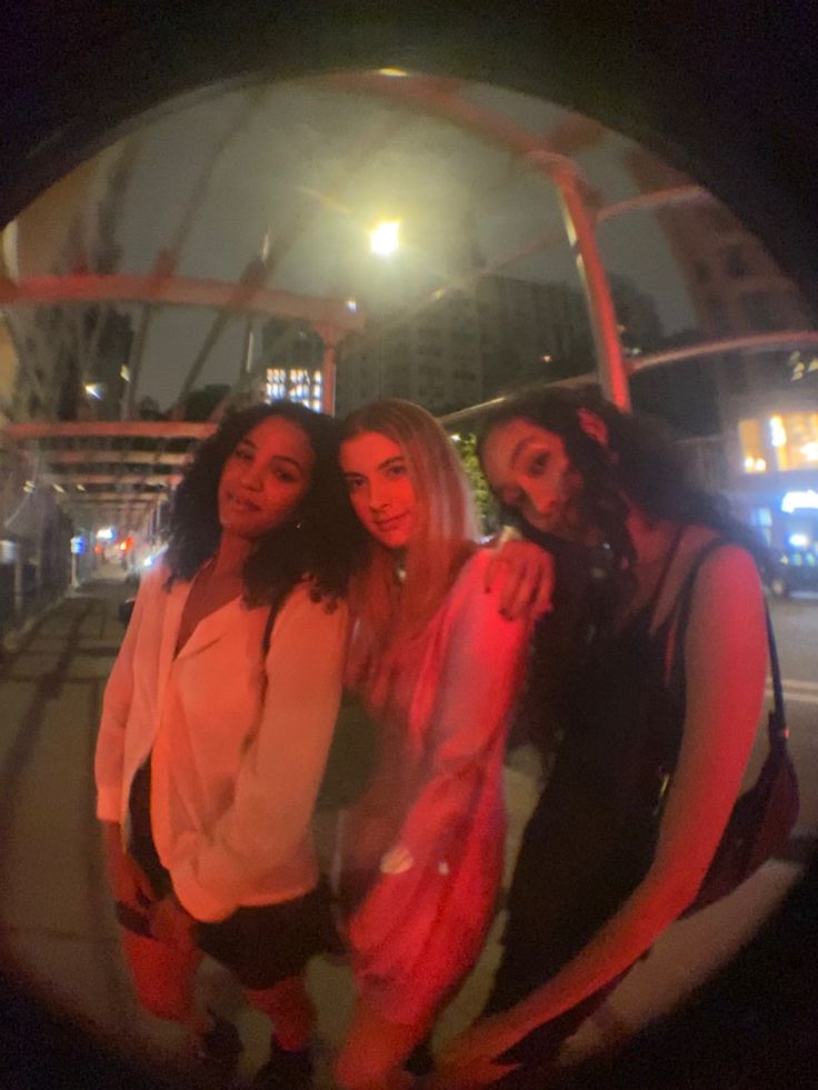 three women are standing in front of a building and one is taking a selfie