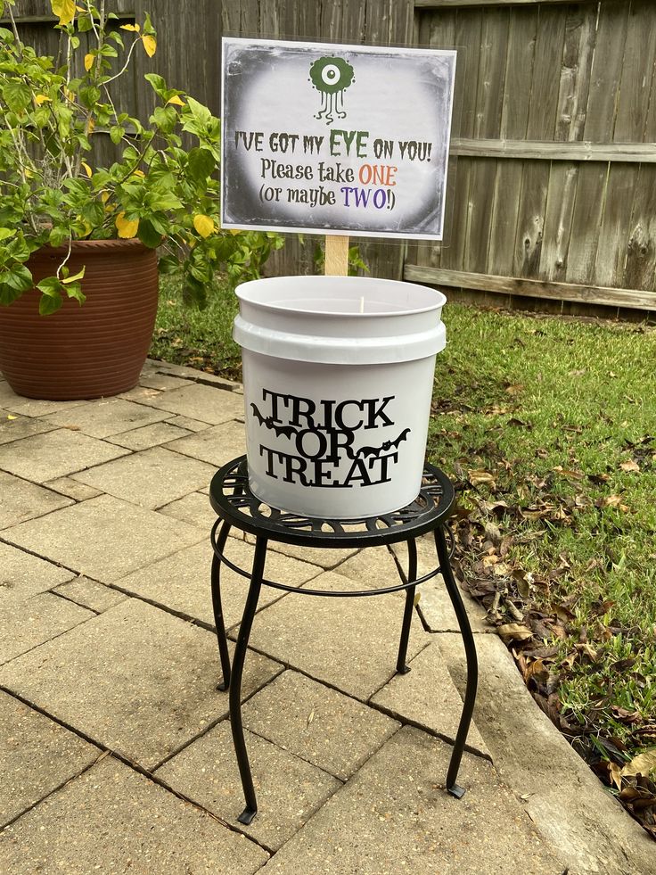 a bucket on a stand with a sign that says trick or treat