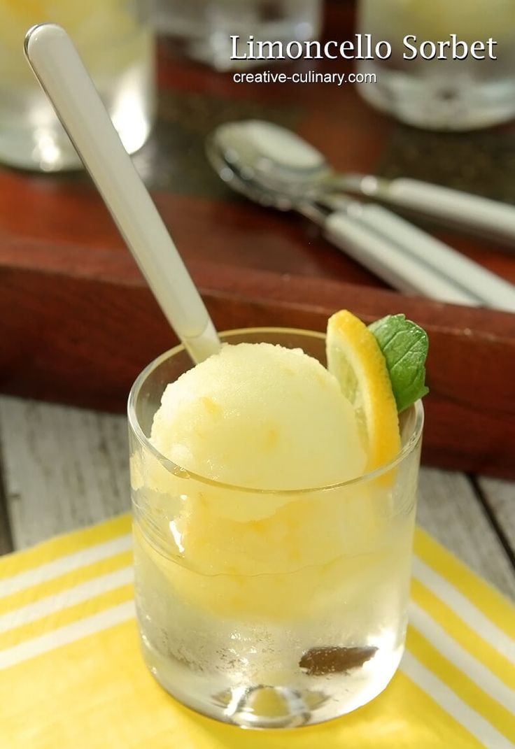 a glass filled with ice cream on top of a yellow table cloth next to silverware