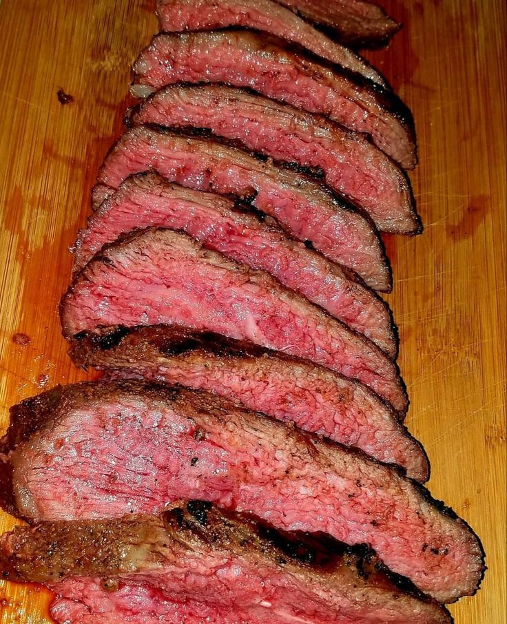 slices of steak sitting on top of a wooden cutting board