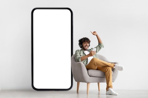 a man sitting in a chair next to an empty white board on the wall and pointing at it