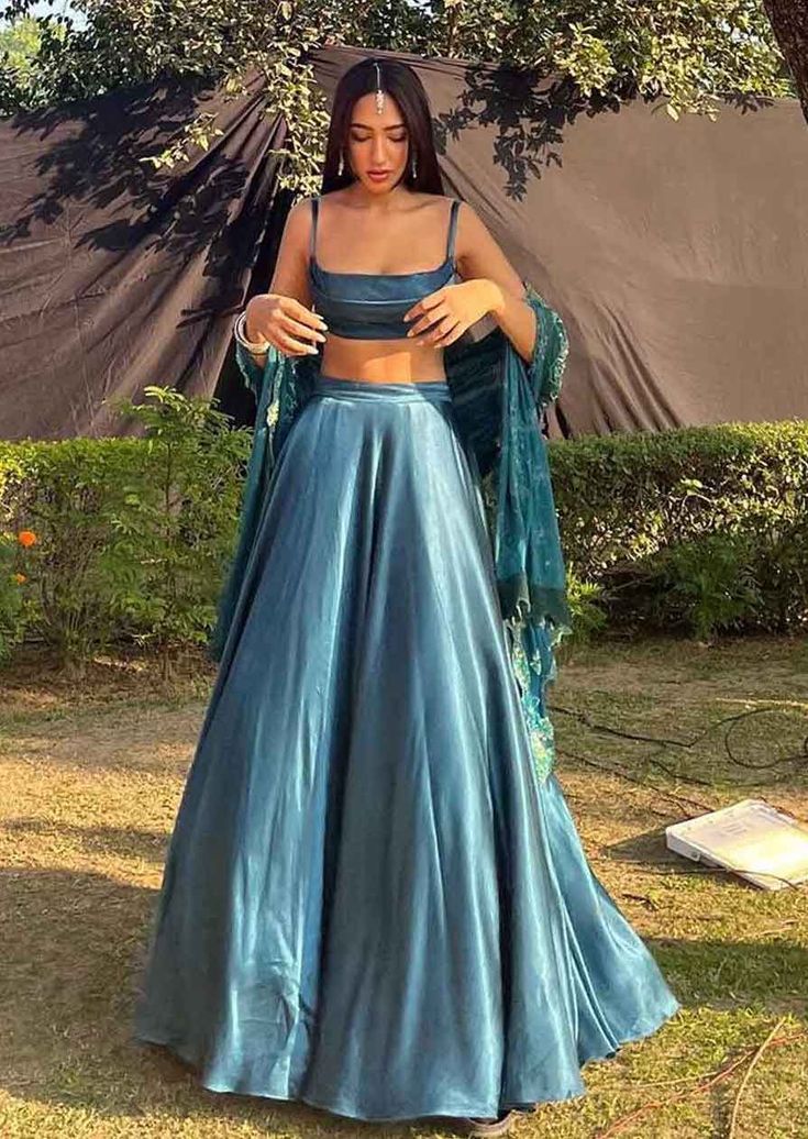 Step into refined elegance with this stunning blue teal lehenga crafted in luxurious gaji silk. The flared skirt is paired with a sleek sleeveless blouse, creating the perfect ensemble for bridesmaids looking to turn heads at sangeet or reception celebrations. A timeless statement piece for any festive occasion. Please note: The dupatta worn by the model is not by the designer. A customized dupatta can be provided upon request for an additional charge. Color: Blue Fabric: Gaji silk Components: S Teal Lehenga, Skirt With Blouse, Lehenga With Blouse, Teal Skirt, Simple Lehenga, Trendy Outfits Indian, Indian Outfits Lehenga, Lehenga Designs Simple, Traditional Indian Dress