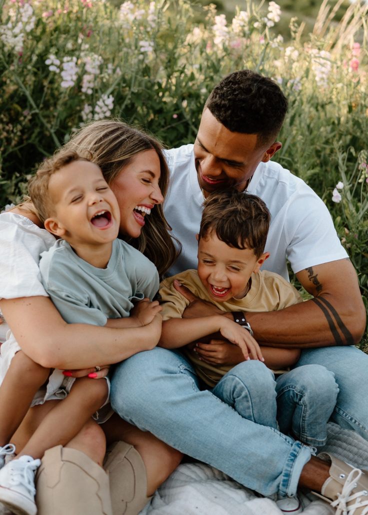 a man, woman and two children are sitting on a blanket in front of flowers